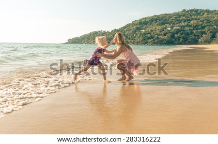 mom and daughter playing on the beach. mom opening the arms to catch the little girl. concept about family and vacations