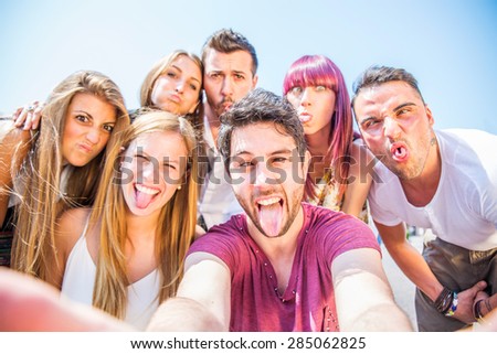 Group of friends grimacing in front of the camera - Young happy people having fun at party and making funny faces while photographing themselves