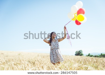 woman with balloons in a wheat field. concept about carefree, airiness and people