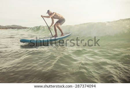surfer with paddle board catching the wave. concept about sport and people