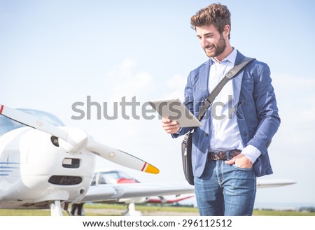 business man with his airplanes. He is walking in the airport with the tablet checking the schedule.