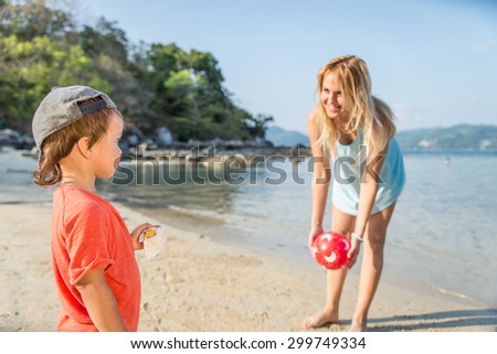 Mom playing with her handsome son on the beach - Happy family on vacation on a tropical beach