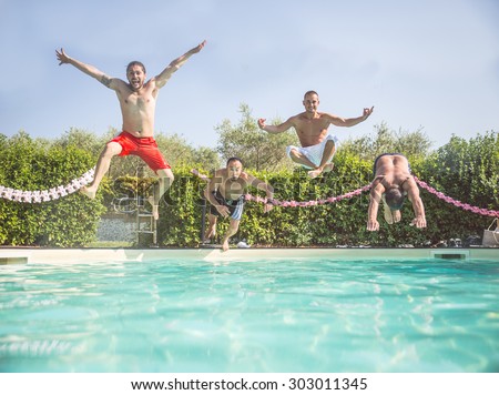 Four friends jumping into a swimming pool - Happy people having fun and diving into water - Tourists on summertime vacation in a tropical resort