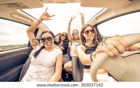 four girls driving in a convertible car and having fun