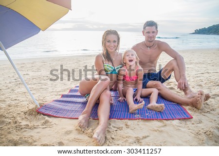 Happy family on the beach smiling and looking at camera - Tourists on vacation on a tropical island