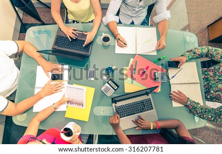 Team of young business people at a meeting - Start up conference, group of investors planning a new strategy - Office desk with computers,phones,notes and other supplies