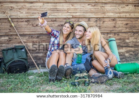 Happy group of friends photographing themselves  - Hikers on excursion in the nature having fun and taking a selfie outside a wooden bungalow