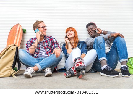Group of friends sitting on the street and talking at mobile phone - Young modern hipsters people having fun with new technologies - Multiracial group representing the addiction to technology