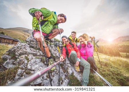 Happy group of friends photographing themselves  - Hikers on excursion in the nature having fun and taking a selfie with action camera stick