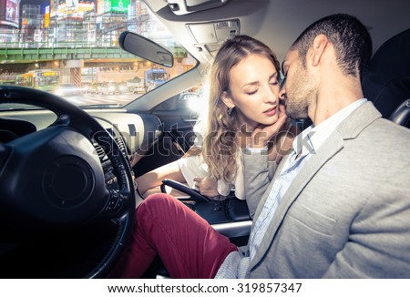 couple kissing each other in the car, traffic jam in the night visible from the street.