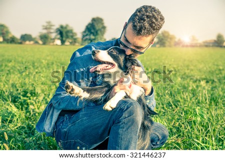 Young man stroking his playful dog - Cool dog and young man having fun in a park - Concepts of friendship,pets,togetherness