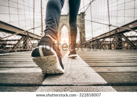 Woman running outdoors - Young sportive girl jogging at sunset on Brooklyn Bridge, close up on shoes