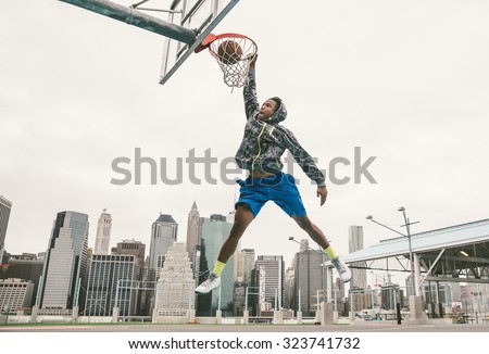 basketball player performing slum dunk on a street court. background with manhattan buildings