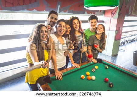 Group of multiracial young people standing next to pool table and taking a selfie - Students spending an evening at pub