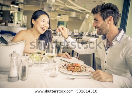 Young couple eating in a restaurant. Man giving food to her beautiful girlfriend. concept about couple, food and people