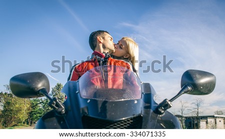 Happy young couple kissing on the motorcycle. Concept about love and transportation