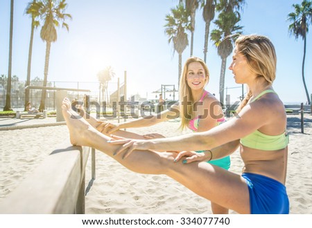 Two sisters making stretching on the beach in Los angeles. sport and fitness