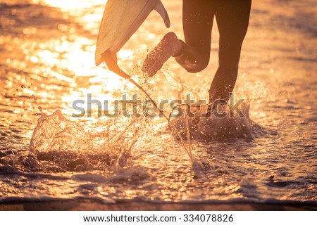 Surfer running in the water with his board. Ready for a great surfing day