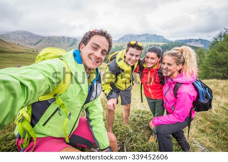 Happy group of friends photographing themselves - Hikers on excursion in the nature having fun and taking a selfie with action camera