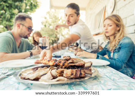 Group of friends having lunch in the garden. concept about barbecue with friends. focus on a plate with meat