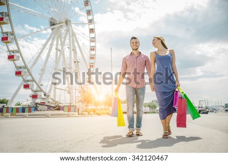 Happy couple laughing and walking while shopping - Young attractive boyfriend and girlfriend with shopping bags outdoors