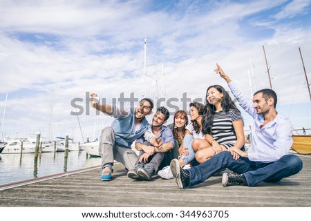 Best friends taking a self portrait - Group of young and happy people on vacation at harbor with sailing boats in the background