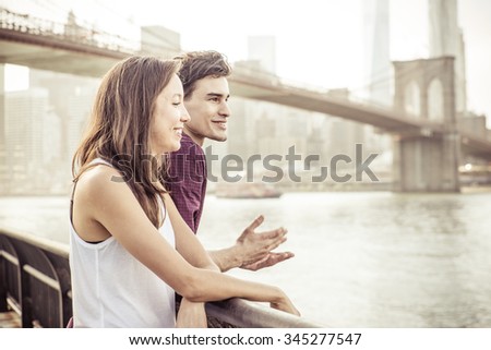 Happy couple talking in front the famous Brooklyn bridge. Concept about traveling, landmarks and people