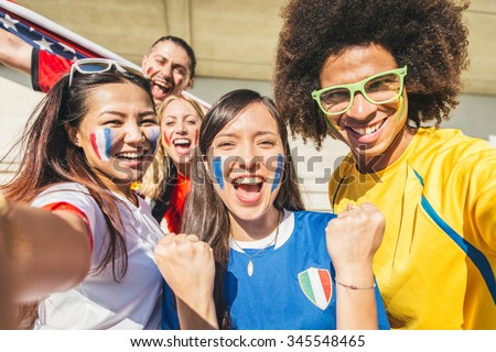 Group of sport supporters at stadium taking selfie - Fans of diverse nations screaming to support their teams - Multi-ethnic people having fun and celebrating on tribune at a sport event