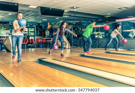 Group of friends at bowling - Young people having fun at bowling, four players throwing balls on the bowling track
