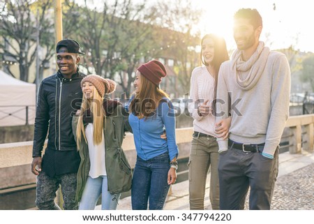 Group of multi-ethnic friends walking on the streets and smiling - Young people having fun outdoors