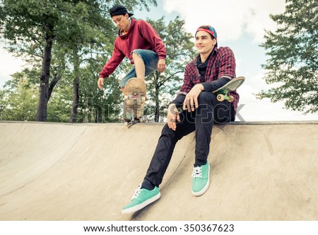 Two skaters practicing at the skate park. Young boys having fun with skateboards