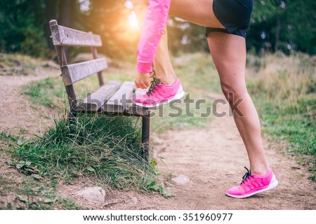 Woman tying shoelaces before start running - Sportive girl jogging in a park , close up on running shoes - Concepts about sport and lifestyle