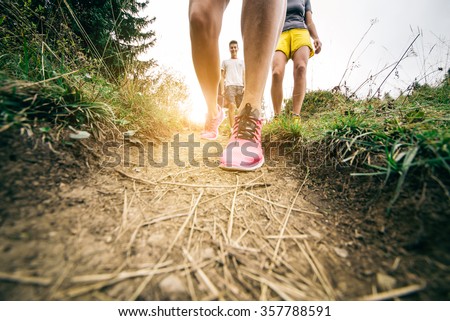 Group of hikers walking in the nature at sunset - Friends taking an excursion on a mountain,close up on shoes