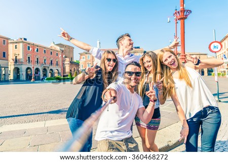 Group of happy friends taking a selfie with stick outdoors - Concept of young people having fun and using new communication technologies