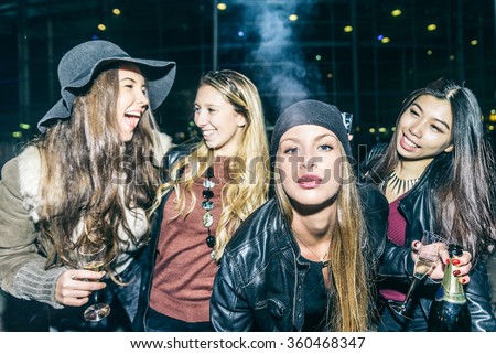 Group of four pretty girls having party, smoking and drinking alcohol - Best friends clubbing in the night, frontal flash to give realism to the scene
