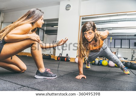 Sportive woman making pushups with one hand - Athlete training in a gym with coach - Girls working out in a fitness center