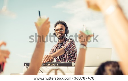 Dj playing at the beach party. Concert outdoor, with people raising drinks and hands to the sky. Entertainment and people concept