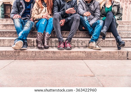 Group of people sitting on a staircase outdoors, close up on low section body - Multiracial friends talking and having fun on a meeting outdoors