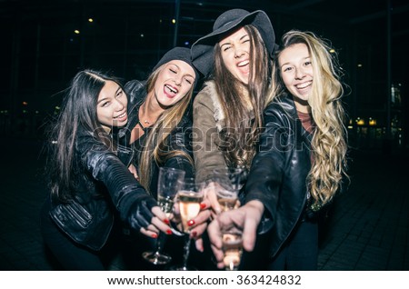 Pretty women toasting champagne glasses and having fun - Four girls drinking sparkling white wine and celebrate before going into club