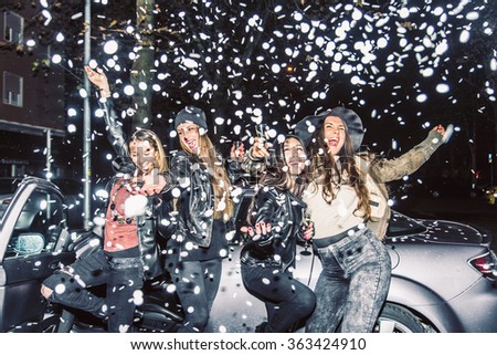 Pretty crazy girls dancing, throwing confetti and drinking wine - Young women partying outdoors before to go in a club