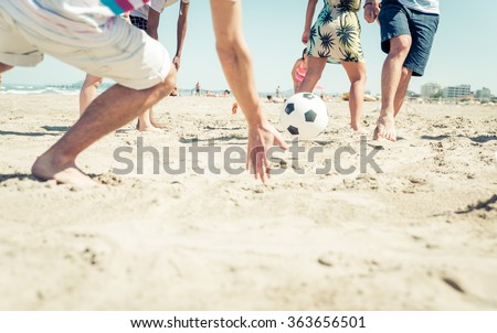 Group of friends having fun on the beach playing soccer. happy people and beach games concept