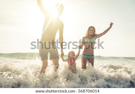 Happy family jumping in the waves, in Karon beach, Phuket. Family enjoying vacations in tropical places. Concept about people and vacations