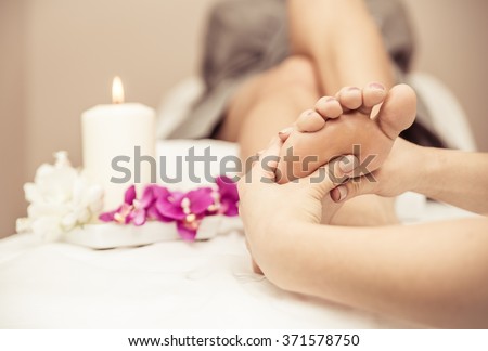 Close up of woman\'s feet and beauty saloon decorations. Beautician making foot massage. Concept about body care, spa and massages