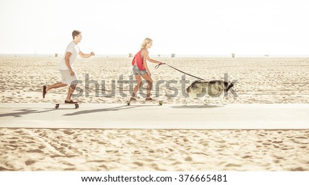 Couple and their husky dog making some sport on the beach with skateboards, Santa monica beach, California