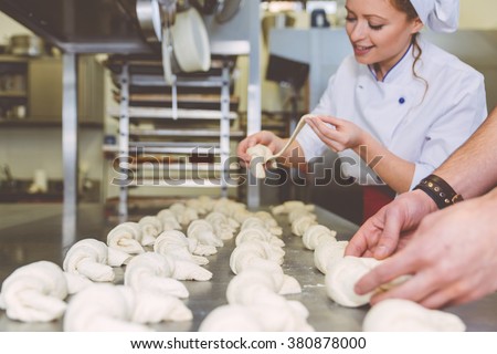 Chef preparing sweet croissant in the pastry shop laboratory. Industrial concept about food. Focus on the sweets