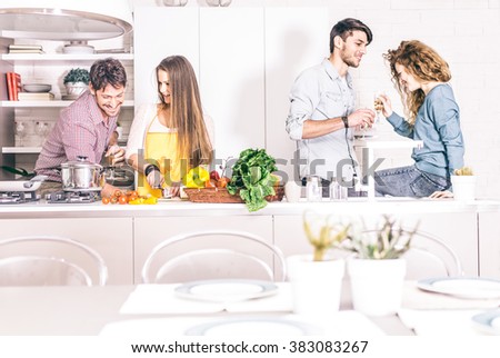 Group of friends at home party, woman cooking dinner for her guests - Young adults talking and having fun at home while preparing a delicious meal