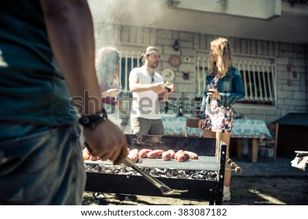 Friends in home garden grilling meat and having fun - Group of people at barbecue party drinking wine