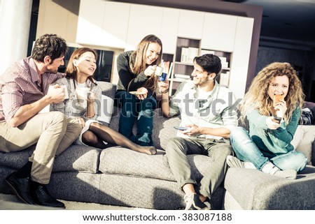 Group of friends talking and having fun while sitting on the couch - Cheerful people meet at friend\'s home for a coffee break