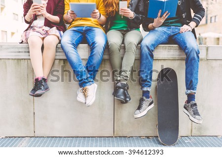 Group of teenagers making different activities sitting in an urban area