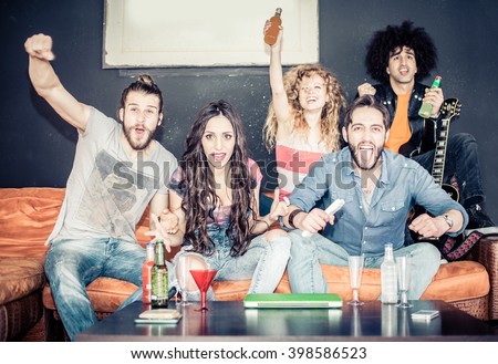 Cheerful friends sitting on the couch and exulting while watching a sport match on tv - Happy young cool people having fun at a home party